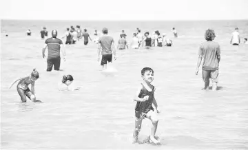  ??  ?? Iraqi youths and children swim in the waters of Lake Habbaniyah.