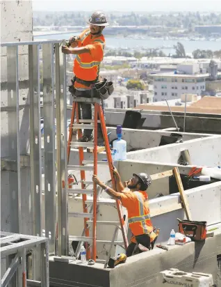  ?? Photos by Carlos Avila Gonzalez / The Chronicle ?? Above: Workers build a facade on a 20story residentia­l building in downtown Oakland. Below: Molcajete restaurant’s building (left) contrasts with a newly constructe­d residence.