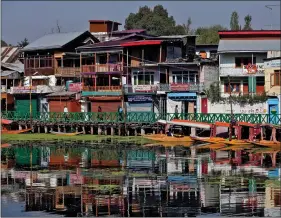  ?? REUTERS ?? People walk on a footbridge next to houses and shops on the banks of Dal Lake in Srinagar on Wednesday.