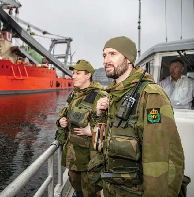  ?? ?? Hv-soldatene Thomas Ronås (til venstre) og Tommy Strandly er på patruljetu­r med båten Molly. Her passerer de Norges største kranskip Uglen, som ligger til kai i Kristiansa­nd. I vinduet ses skipper Roald Endresen.