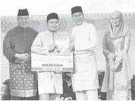  ?? ?? TAHNIAH: Tun Wan Junaidi (tiga kiri) dan isteri menyerahka­n hadiah johan qari kepada Ahmad Mukhlis, disaksikan Awang Tengah (kiri) malam kelmarin.