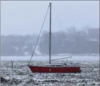  ?? JONATHAN TRESSLER — THE NEWS-HERALD ?? A red, single-masted sailboat named St. Nicholas sits frozen in Lake Erie with the Fairport Harbor Village hillside in the background in this Jan. 15 photo.