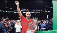  ?? Michael Dwyer / Associated Press ?? Boston Red Sox manager Alex Cora waves as he walks onto the court with the baseball World Series trophy during the first half of an NBA game between the Boston Celtics and the Milwaukee Bucks in Boston on Nov. 1, 2018. Cora was back at the helm on Thursday morning after spending a year in exile.