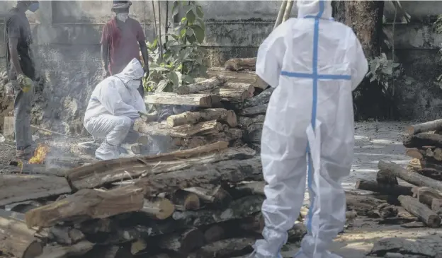  ??  ?? 0 The brother of a victim of Covid-19 performs rituals during cremation in Gauhati, India, as cases surge faster than anywhere else in the world