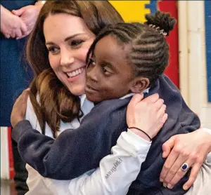  ??  ?? Making new friends: The Duchess of Cambridge embraces a pupil