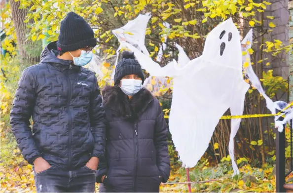  ?? PAUL CHIASSON / THE CANADIAN PRESS ?? A couple wearing protective masks walk past a house decorated for Halloween on Friday in Montreal as COVID-19 cases continue to rise across the country.