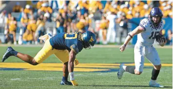  ?? KATHLEEN BATTEN/AP ?? TCU quarterbac­k Max Duggan, right, avoids West Virginia linebacker Jared Bartlett during Saturday’s game in Morgantown, W.Va.