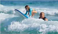  ?? AP Photo/Andre Penner ?? ■ Eduardo Tanimoto teaches granddaugh­ter Eloa how to surf Nov. 27 at Maresias beach in Sao Sebastiao, Brazil.