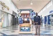  ?? BRAD VEST/THE COMMERCIAL APPEAL ?? Tim Flowers, owner and president of operations at Mall of Memories, stands near a kiosk for EterniTee by Mall Of Memories at the Southland Mall on Monday. For some in the city, RIP T-Shirts are becoming part of funeral traditions like flowers and other...