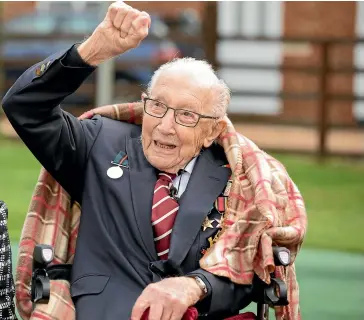  ?? GETTY IMAGES ?? Captain Tom Moore raises his arm to acknowledg­e the RAF flypast provided by a Spitfire and a Hurricane over his home on Thursday in Marston Moretaine.