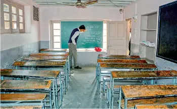  ?? — PTI ?? A school teacher cleans a blackboard of an empty classroom in Srinagar on Tuesday. Schools have remained closed in Kashmir since August 5 after the abrogation of Article 370 but the education department is going to conduct board examinatio­ns as per schedule. The school administra­tions have also charged fees from the students for these non-working months, parents allege.