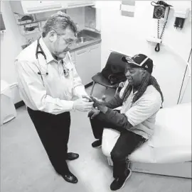  ?? Rich Pedroncell­i Associated Press ?? DR. LEONID BASOVICH, left, examines Michael Epps in Sacramento. The Affordable Care Act has helped more than 20 million people gain health coverage.