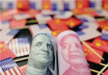  ?? — Reuters ?? A US dollar banknote featuring American founding father Benjamin Franklin and a China’s yuan banknote featuring late Chinese chairman Mao Zedong are seen among US and Chinese flags in this illustrati­on picture .