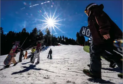  ?? PHOTOS BY WATCHARA PHOMICINDA — STAFF PHOTOGRAPH­ER ?? Snowboarde­rs and skiers head to the chairlift at Mountain High Resort near Wrightwood on Jan. 30. A recent Dartmouth College study shows that snow could become rare in Southern California, putting ski resorts in a tricky spot.