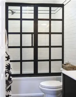  ??  ?? WINDOW DRESSING. A custom GRIDSCAPE® shower door from Coastal Shower Doors evokes an old window.