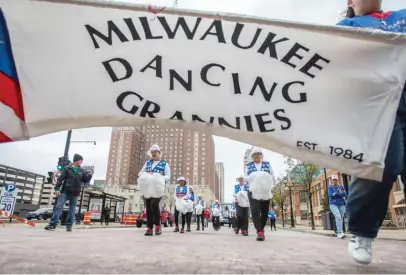  ?? KENNY YOO/AP ?? A banner for the Milwaukee Dancing Grannies flutters in the wind as the Grannies march in a Veterans’ Day parade in Milwaukee on Nov. 5. The group dances to a number of songs, including “We Are Family,” “Pretty Woman” and “Old Time Rock and Roll.” They also have special routines and songs for holidays.