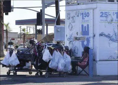  ?? PHOTO CHRIS MCDANIEL ?? Two unidentifi­ed homeless people shelter in the shade of a water vending machine along Fourth Street Thursday afternoon. Securing gainful employment in El Centro apparently is so di cult that the city has been named by one website as the worst city in the USA to find a job.