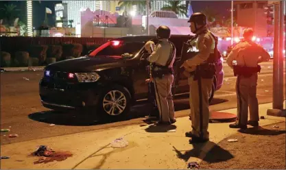  ?? The Associated Press ?? Police stand at the scene of a shooting along the Las Vegas Strip on Monday. More than 50 people were killed when a man began shooting at concertgoe­rs from the 32nd floor of a nearby hotel.The man later killed himself.