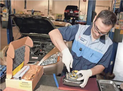  ??  ?? Erland Zeka installs a new air bag inflator as he performs the Takata service recall on a 2005 Honda Accord in Farmington Hills, Michigan, in 2015. JEFF KOWALSKY/EPA