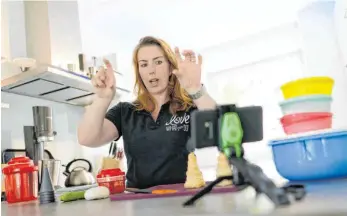  ?? FOTO: HENNING KAISER/DPA ?? Daniela Sigmund demonstrie­rt in einer gestellten Szene Küchenhelf­er für eine virtuelle Tupperpart­y. Die Party-Managerin nutzt digitale Vertriebsw­ege, um ihre Waren zu bewerben.