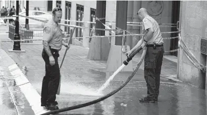  ?? JERRY JACKSON/BALTIMORE SUN ?? City firefighte­rs clean the sidewalk on Light Street following Friday’s shooting. The victim, a 22-year-old woman, is in stable condition.