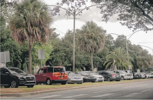  ?? EMILY KASK/AFP VIA GETTY IMAGES ?? Cars are parked on higher ground to protect them from possible street flooding in New Orleans on Monday.