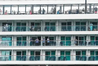  ?? Marta Lavandier / Associated Press ?? Passengers look out from the Norwegian Pearl cruise ship Wednesday as it sails back to Portmiami. The ship left Monday on a trip to the Panama Canal, but it had to return after several crew tested positive for COVID-19.