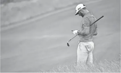  ?? PHOTOS BY MICHAEL MADRID, USA TODAY SPORTS ?? Dustin Johnson takes a break to look at his cellphone during a U.S. Open practice round Wednesday at Erin Hills in Wisconsin.