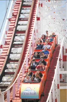  ?? Photos by Peter DaSilva / Special to The Chronicle ?? Riders go hands-free during one of the drops on the Giant Dipper at the Santa Cruz Beach Boardwalk. The Giant Dipper roller coaster at the Santa Cruz Beach Boardwalk, above and left, is turning 93 this year.