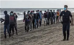  ??  ?? Gran Canaria: Bootsflüch­tlinge aus Marokko werden von der Polizei nach ihrer Ankunft vom Strand wegeskorti­ert.