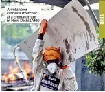  ??  ?? A volunteer carries a stretcher at a crematoriu­m in New Delhi (AFP)