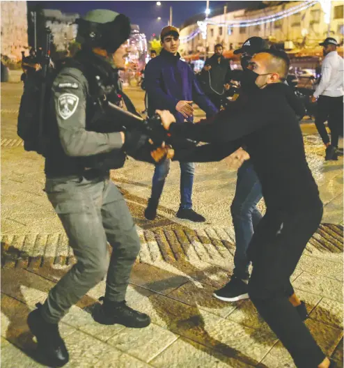  ?? AHMAD GHARABLI / AFP VIA GETTY IMAGES FILES ?? A Palestinia­n protester pulls on the weapon of a member of the Israeli security forces in Jerusalem’s Old City.