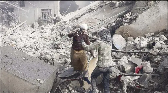  ??  ?? Two Syrian sisters run across the rubble to hug after finding each other alive following an air strike in the besieged rebel-held Eastern Ghouta area near Damascus on Sunday.