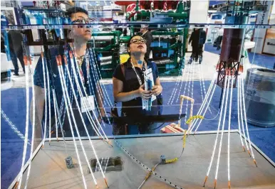  ?? Brett Coomer / Houston Chronicle ?? Elvis Fragoso, left, and Maria Guadalupe look over a model showing platform mooring lines on Monday at the WireCo booth during the 50th Offshore Technology Conference.