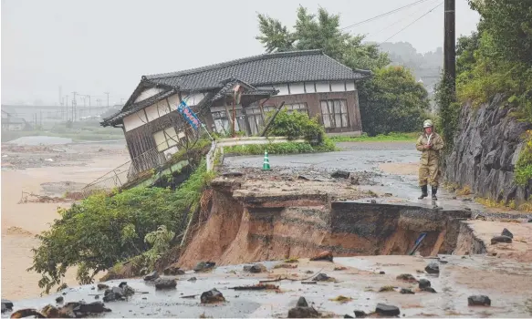  ?? Picture: AFP ?? A resident checks a collapsed roadside near a damaged house following heavy flooding in Asakura, Fukuoka prefecture, in Japan.