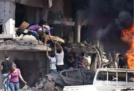  ?? THE ASSOCIATED PRESS ?? Syrians carry the body of a victim from a building damaged in twin bombings in the Kurdish town of Qamishli, Syria, that killed at least 37 people.