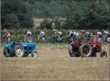  ?? PETER DEJONG — THE ASSOCIATED PRESS ?? The pack rides past farm tractors during the eighteenth stage of the Tour de France cycling race over 171 kilometers with start in Trie-surBaise and finish in Pau, France, Thursday, July 26.