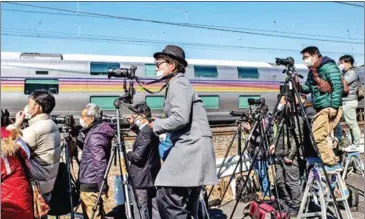  ?? AFP ?? Japanese enthusiast­s take pictures of luxury charter train service Cassiopeia being hauled by a class EF81 dual-voltage electric locomotive on February 28.