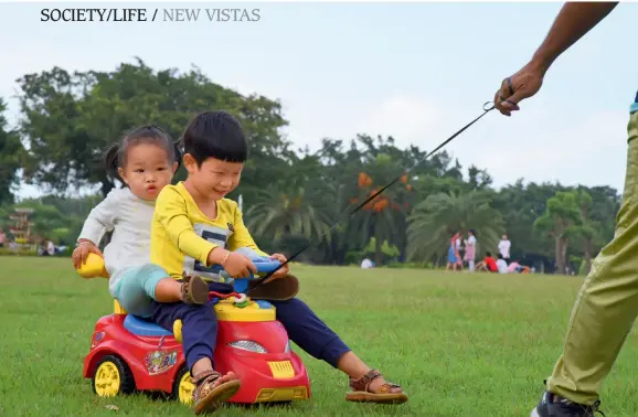  ??  ?? On November 3, 2018, in Haikou, Hainan Province, a father is playing with his daughter and son in the Wanlu Park, an open tropical seaside ecological landscape park. With the full implementa­tion of the two-child policy in China, some families are well prepared for parenting.