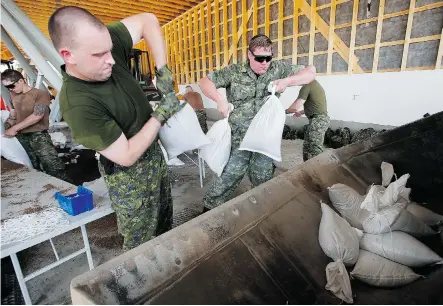  ?? John Woods/The Canadian Press ?? Military personnel helped fill and load sandbags in Portage la Prairie, Man. last week, reinforcin­g dikes and riverbanks.