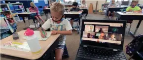  ?? SENTINEL ?? Second grade student Mason Fiore does classwork while next to a laptop with the images of students working at home in teacher Jennifer Kumlien’s class at Lake Country School in Hartland in September.