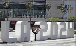  ?? Associated Press ?? Yoga instructor Michale Phillip poses Friday with a Los Angeles 2024 sign outside of the Staples Center in Los Angeles.