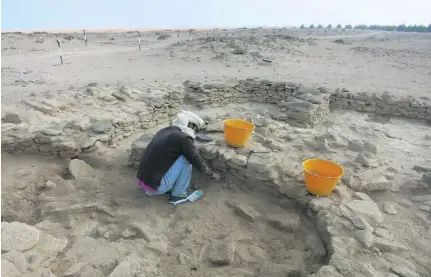  ?? Courtesy Abu Dhabi TCA ?? Abdulla Al Kaabi, above, who discovered the remains, at work on site on Marawah. Project director Dr Mark Beech, right, makes notes as a colleague cleans and preserves finds at village MR II. Dr Beech said the dig shines light into life in the Western...