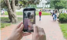  ??  ?? A woman plays Pokemon Go in a park. The game already has more daily users than the dating app Tinder. JIM WATSON/AFP/GETTY IMAGES