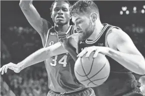  ?? CARLOS OSORIO, AP ?? Michigan center Hunter Dickinson drives on Ohio State center Felix Okpara Sunday. Dickinson scored 26 points in the Wolverines' 77-69 win.