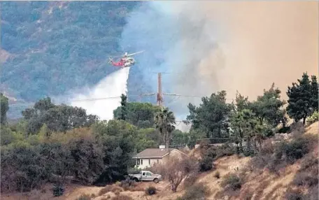  ?? Photograph­s by Roger Wilson Burbank Leader ?? A LOS ANGELES FIRE DEPARTMENT helicopter drops water on a brush fire threatenin­g homes in the Verdugo Mountains near Tujunga. By 9:30 p.m. the blaze was about 10% contained, and no injuries or structure damage were reported, an LAFD spokesman said.