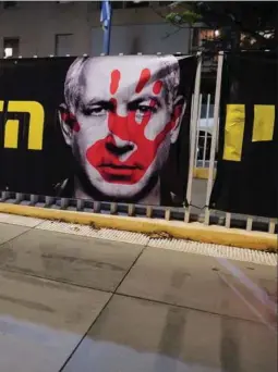  ?? ?? Mange israelere holder Netanyahu ansvarlig for, at Hamas-angrebet kunne ske, og ønsker premiermin­isterens afgang. Her ses en plakat med en blodig hånd over Netanyahus ansigt.
Foto: Alexandre Meneghini/Reuters
