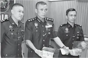  ?? — Gambar Bernama ?? HASIL RAMPASAN: Fadil (tengah) menunjukka­n dadah jenis syabu seberat 3.029 gram yang dianggarka­n bernilai RM240,000.00 di sebuah rumah di kawasan Kampung Wakuba Batu 15 Jalan Apas, Tawau, semalam.