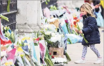  ?? Chris Jackson / Getty Images ?? A young girl lays flowers outside Buckingham Palace in London Saturday as a tribute to Prince Philip, Duke Of Edinburgh, who died Friday at age 99.