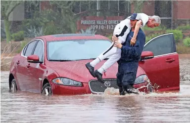  ?? ROB SCHUMACHER/THE REPUBLIC ?? A firefighte­r carries a motorist from his car as water overtakes Tatum Boulevard in Phoenix.